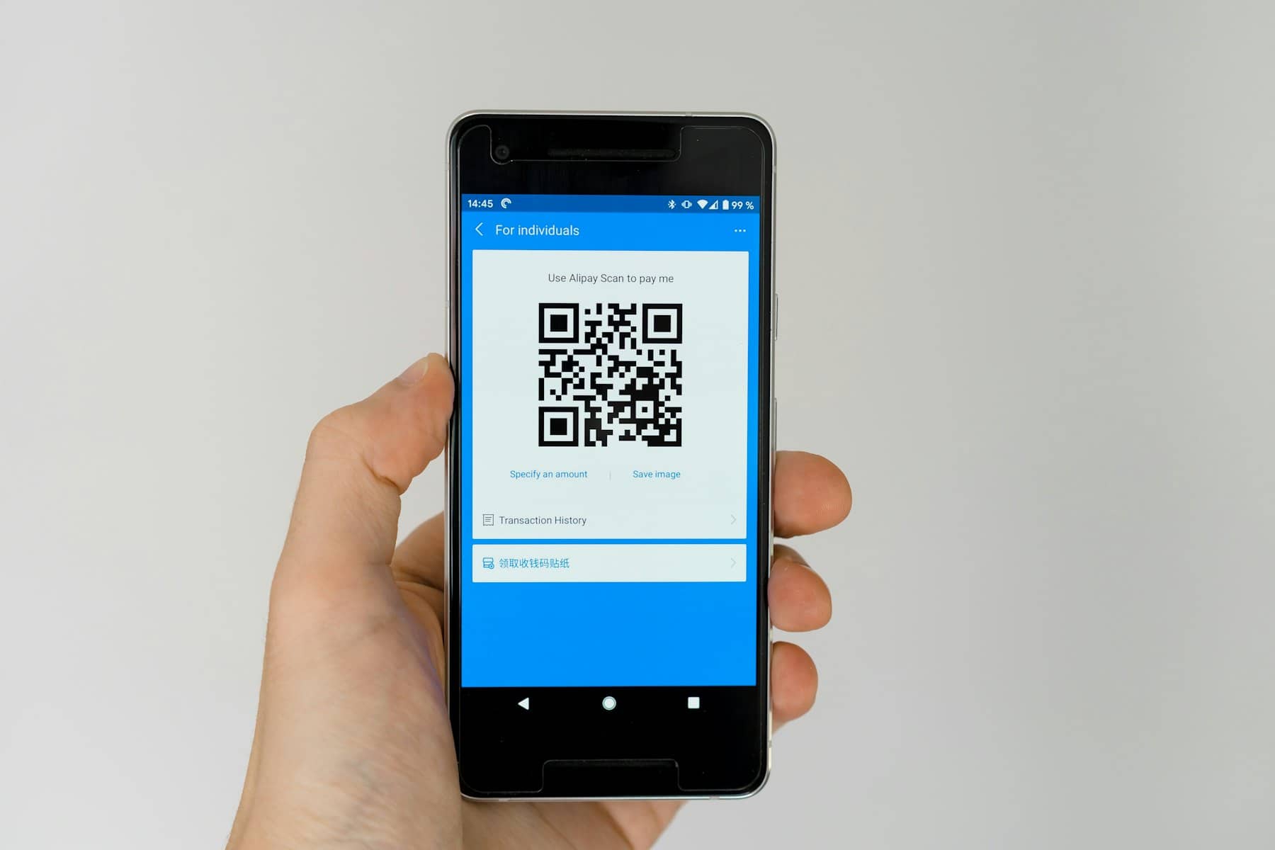 A hand holding a phone showing a QR code