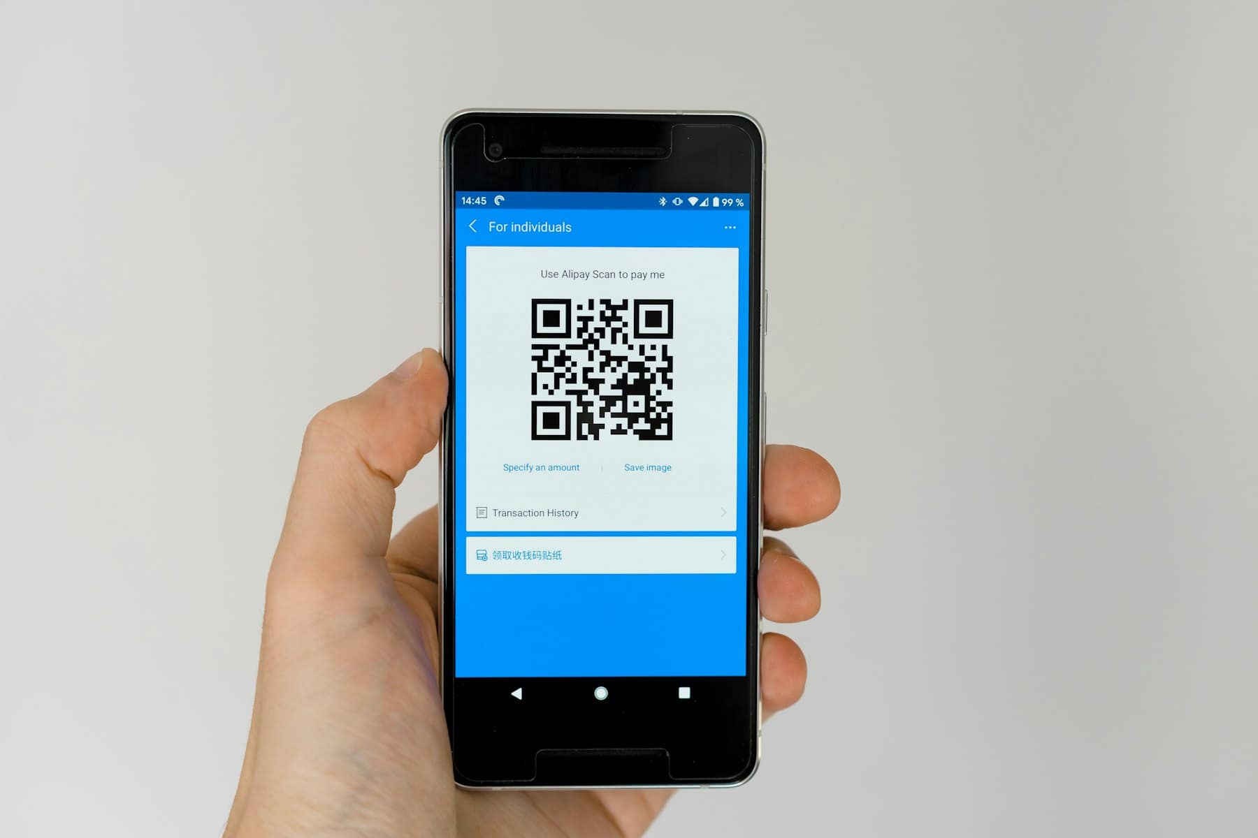A hand holding a phone showing a QR code